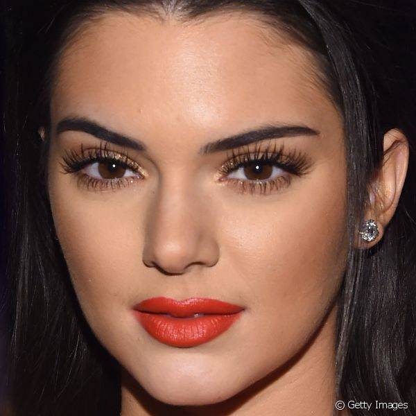 Kendall Jenner foi ao amFAR 2015 repetindo o vermelho tomate do vestido no batom e aplicou um contorno para deixar os lábios mais volumosos. Os cílios postiços com acabamento natural foram outro destaque do look da top.